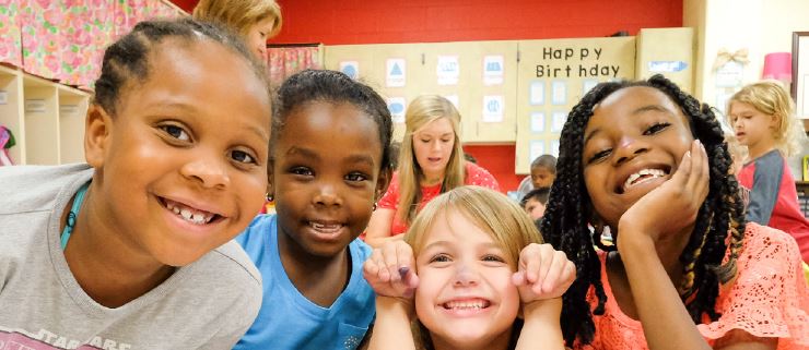   Students in a classroom looking at camera, smiling